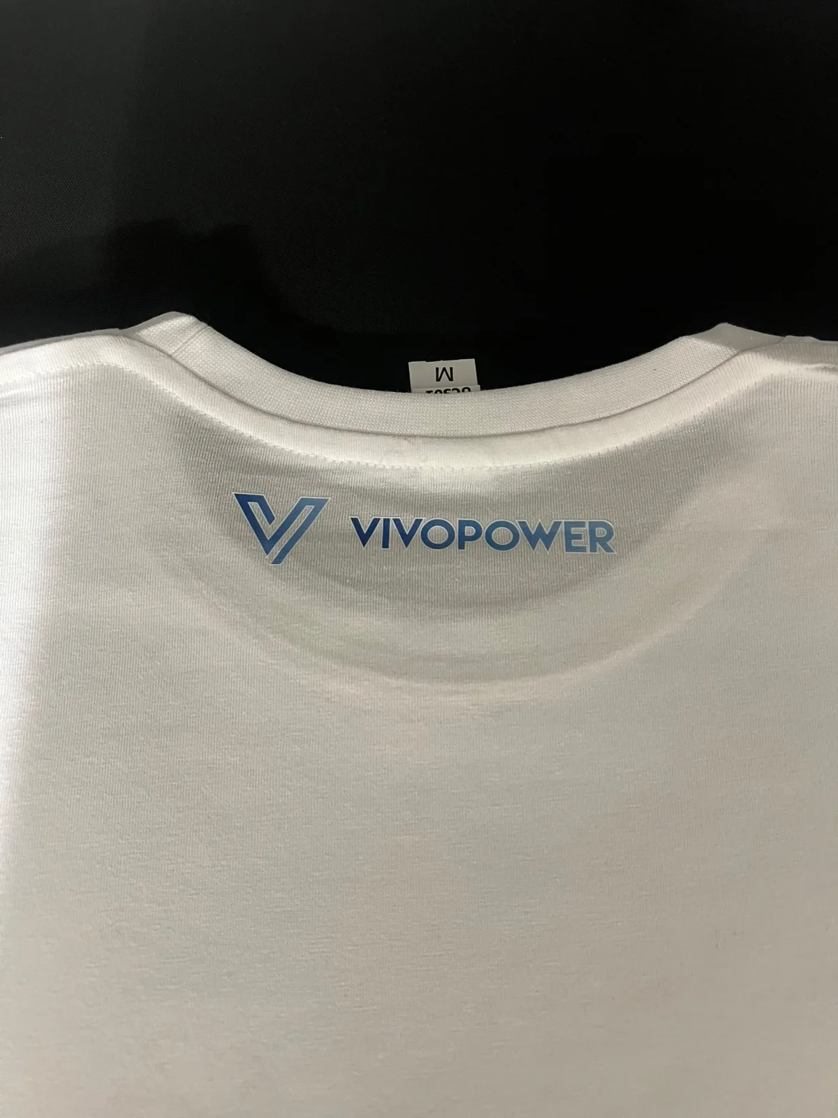 Close-up of a small logo printed below the back neck of a white premium cotton T-shirt